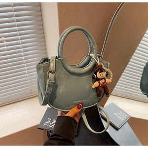 Detail of light blue crescent bucket bag with pearl chain and cartoon pendant accessory