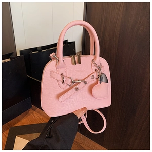 Detail of pink shell bag with lychee pattern leather and heart-shaped pendant accessory