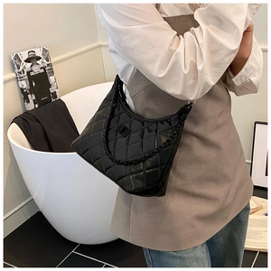 Close-up of black quilted shoulder bag featuring a chain strap and elegant turn-lock closure