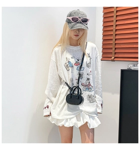 Detail of a black leather mini crossbody bag styled with a white graphic ruffle t-shirt