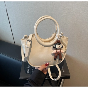 Detail of beige half-moon bucket bag with pearl chain and matte PU leather texture