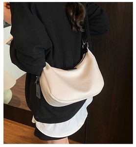Vue de dos d'un sac demi-lune crème en cuir grainé avec une large bandoulière noire logo
