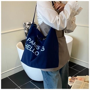 Detail der dunkelblauen Canvas-Tasche mit PARIS HELLO Aufdruck an einem Model getragen