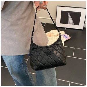 Detail view of black quilted leather shoulder bag with metal chain strap and turn-lock