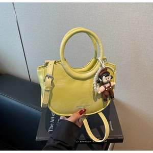 Detail of avocado green crescent bucket bag with metal ring handle and cute doll pendant