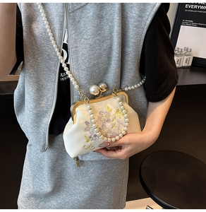 Detailed embroidery and pearl accents on elegant white evening bag with gold metal clasp