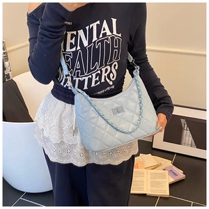 Detail of light blue quilted underarm bag with silver square lock and chain strap