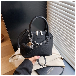 Detail of black lychee grain leather shell bag featuring heart pendant and silver hardware