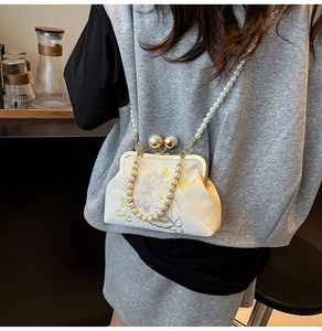 Detailed embroidery of purple flowers and pearl strap on ivory satin evening bag