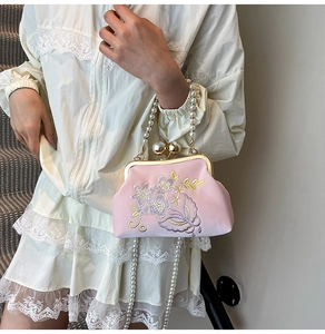 Detail of pink satin evening bag with floral butterfly embroidery and pearl handle strap