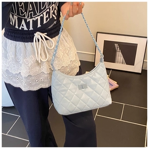 Detail of light blue quilted crossbody bag with matching chain strap and woven texture