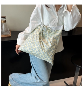 Close-up of blue floral tote bag with lace trim and You're So Cute text detail