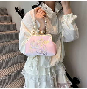Macro view of detailed floral embroidery and pearls on a vintage pink satin shell bag