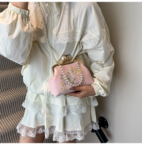Detailed view of floral embroidery and pearl clasp on the pink elegant evening bag