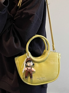 Fashionable bright yellow bucket bag with pearl chain and cartoon charm in hand