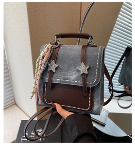 Detail of vintage denim and brown leather backpack featuring metal star buckles and studs