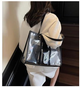 Detailed view of a transparent PVC tote bag with black PU leather trim on a shoulder