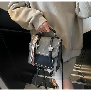 Detail of gray leather backpack with silver star studs and printed decorative scarf