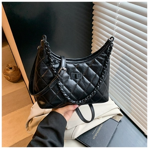 Close-up of black quilted shoulder bag with chain strap and elegant turn-lock closure detail