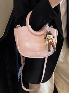 Pink crescent bucket bag with pearl chain and doll pendant shown on a model