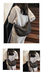Detail of minimalist black nylon crescent tote bag with drawstring texture and adjustable strap