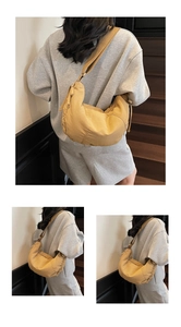 Detail of a ginger yellow crescent crossbody tote bag worn by a model on stairs