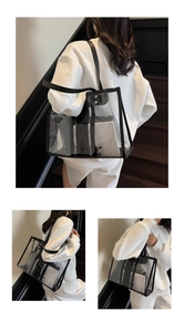 Detail view of large transparent PVC tote bag with black faux leather trim and shoulder strap