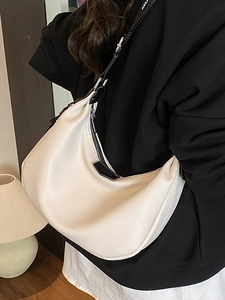 Sac hobo beige minimaliste avec bandoulière réglable et texture grainée porté par un mannequin
