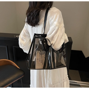 Minimalist transparent PVC tote bag with black leather straps shown in a lifestyle setting