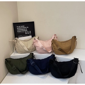 Detailed view of assorted colors nylon crescent crossbody bags on a white tiered display