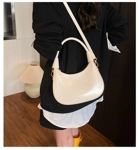 Detail of creamy white crescent moon bag with golden hardware and adjustable strap