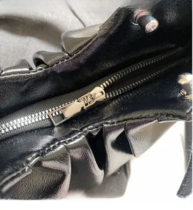 Close-up of smooth silver metal zipper and black pleated oil wax leather texture