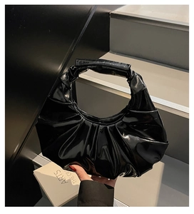 Close-up of glossy black patent leather handbag with pleated texture and moon shape