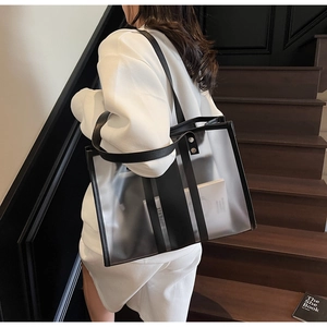 Detail of transparent large tote bag with black leather trim and vertical stripes on shoulder