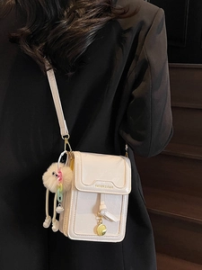 Minimalist off-white leather shoulder bag with plush pendant and gold lettering detail