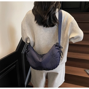 Detail of navy blue nylon crescent bag with wide fabric strap and side drawstring texture