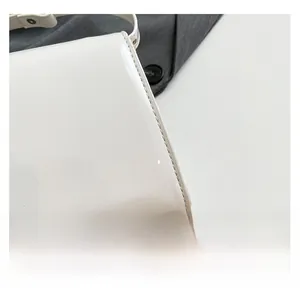 Détail du sac à bandoulière en cuir verni blanc montrant les coutures et la texture