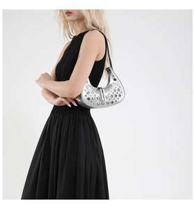 Silver hobo bag with metal rivets on model wearing black dress for modern chic look