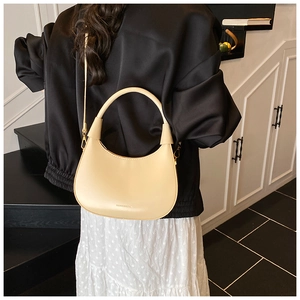 Detailed back view of a beige crescent hobo bag worn as a shoulder bag in minimalist setting