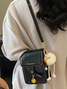 Minimalist black glossy leather crossbody phone bag with trendy plush monster charm