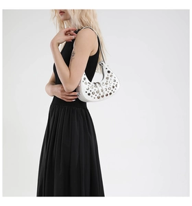 White crescent underarm bag with metal rivet details shown on a model's shoulder