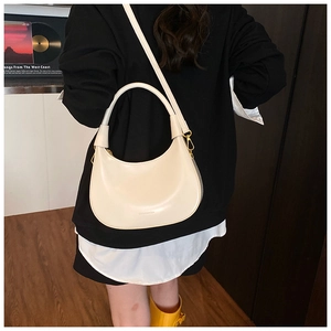 Chic cream white crescent bag shown being worn over the shoulder in a lifestyle setting