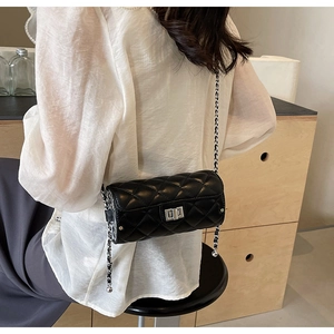 Détail d'un sac cylindrique noir matelassé avec fermoir porté à l'épaule par un mannequin
