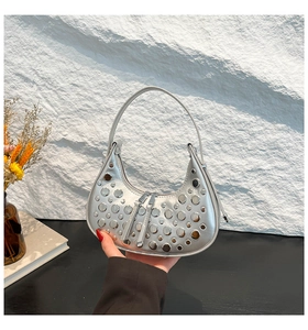 Detail of silver crescent bag with polished metal rivets and metallic finish