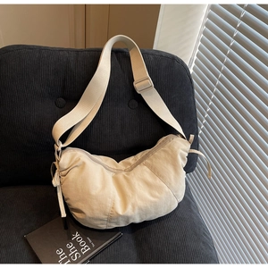 Close-up of ivory nylon crescent tote bag on sofa with stylish light and shadow