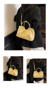 Detail of creamy yellow pleated oil wax leather handbag with unique circular handle