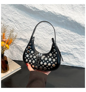 Detail view of black crescent bag with silver metallic studs and dual zipper closures
