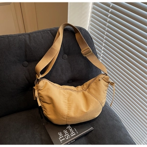 Detail of khaki crescent crossbody bag showing side drawstring and adjustable wide strap