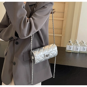 Détail du sac cylindre argenté matelassé avec finition métallique et chaîne