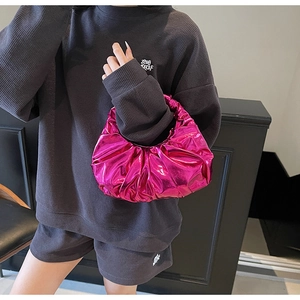 Close-up of metallic pink ruched handbag held by model wearing a dark grey knit set